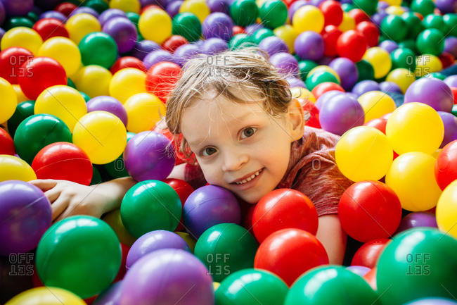 Smiling child having fun with colorful balls at indoor playground