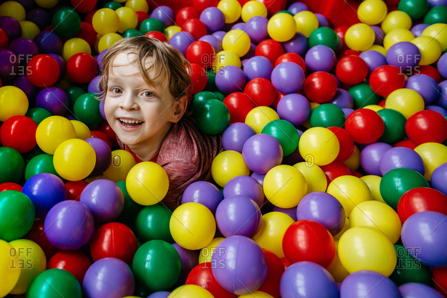 Smiling child having fun with colorful balls at indoor playground
