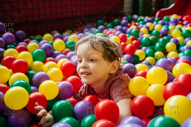 Smiling child having fun with colorful balls at indoor playground