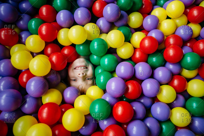 Close up of a happy child's face dived in a pool of colorful balls
