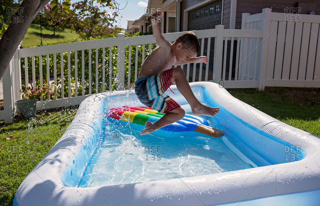 Boy Jumping Into Inflatable Pool Stock Photo Offset