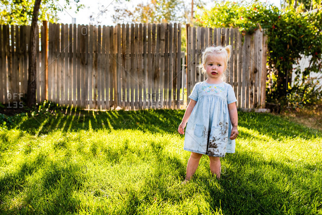 Little girl with muddy face walking in her backyard