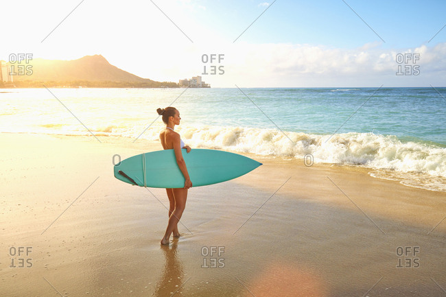 Pacific Islander woman holding surfboard on beach