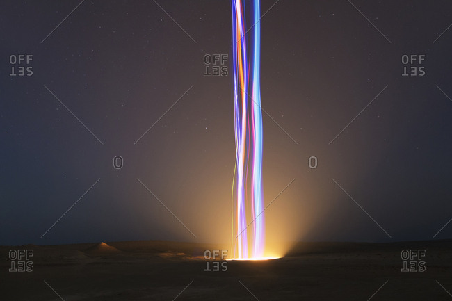 Multicolor light beams in glowing hole in desert