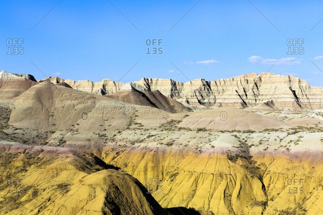 Layered rock formations under blue sky, Badlands National Park, South Dakota, United States