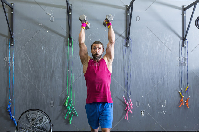 Mixed Race man lifting dumbbells in gymnasium