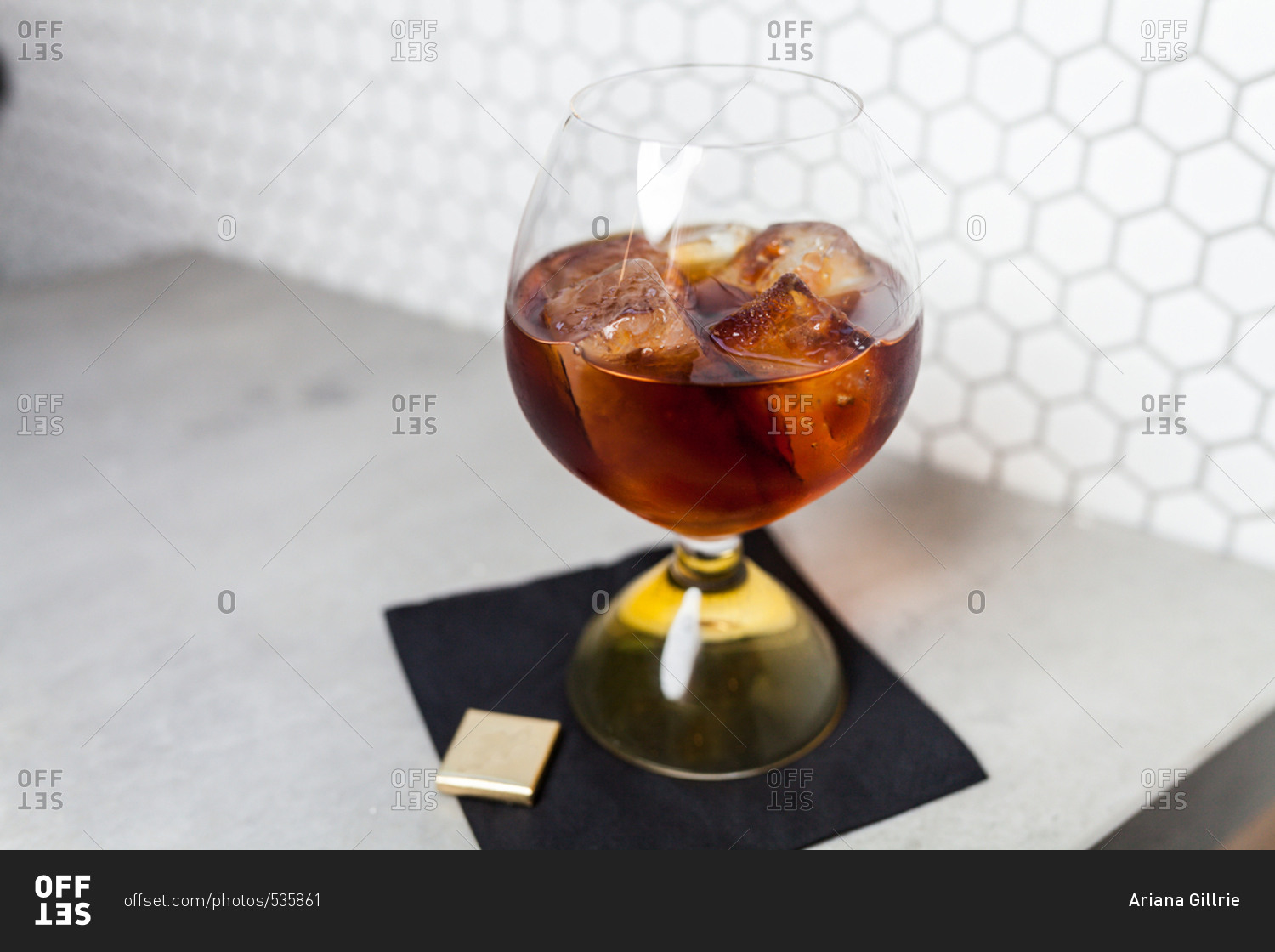 Dark alcoholic drink served in a glass with ice cubes