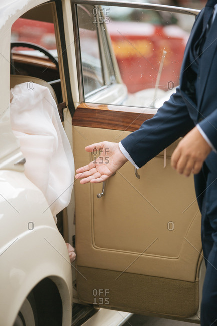 Groom giving hand to bride in car
