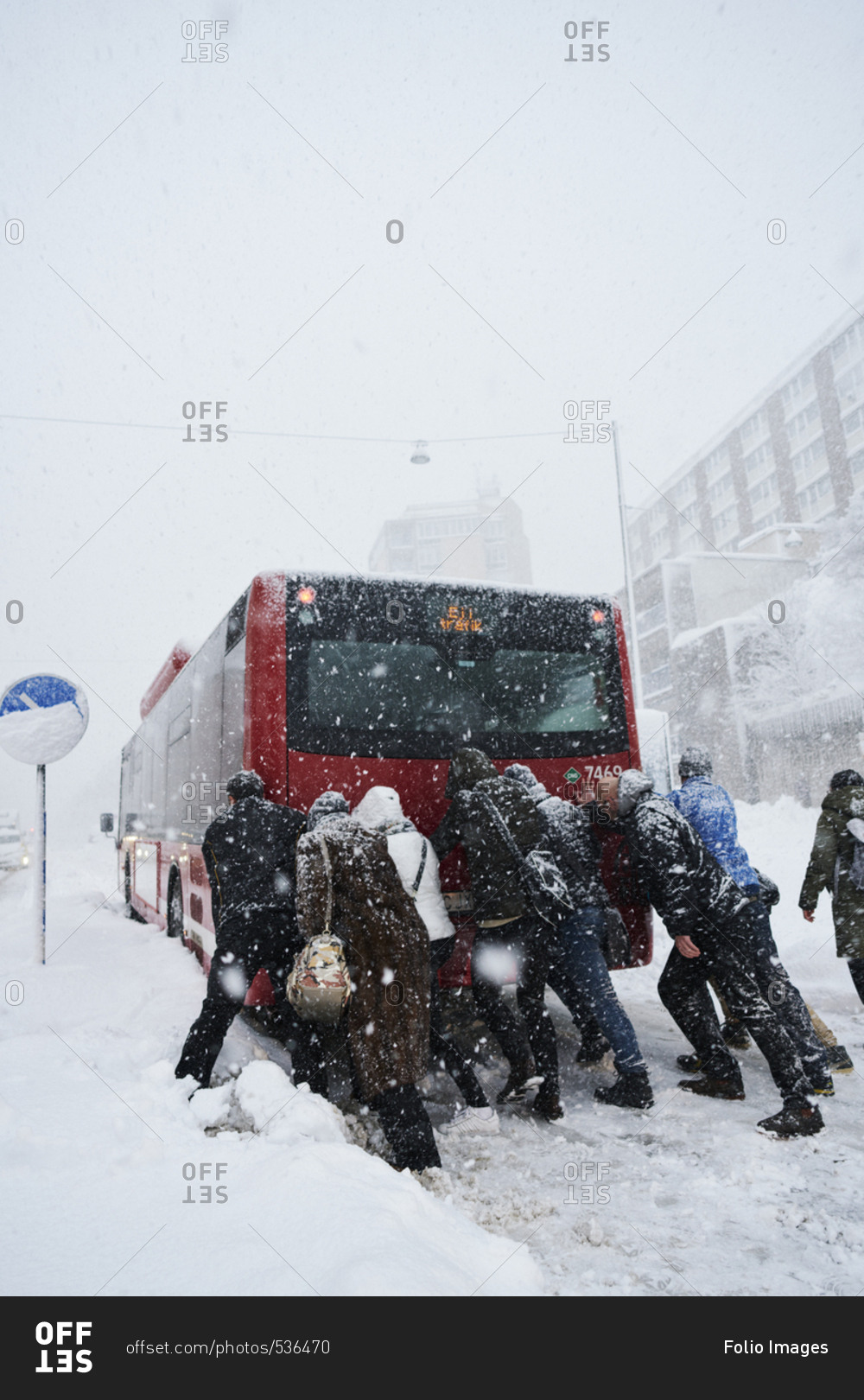 Sweden, Stockholm, Sodermalm, Folkungagatan, People pushing bus in winter