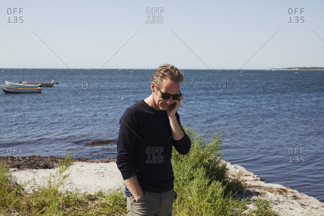 Sweden, Skane, Hollviken, Man talking on phone by sea