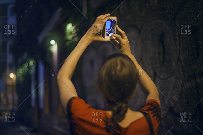 Germany, Berlin, Woman taking photo in city at night