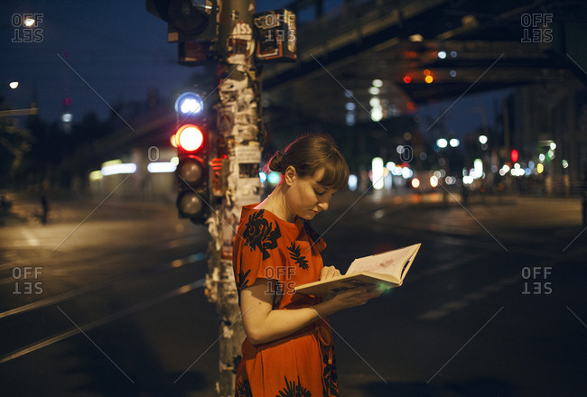 Germany, Berlin, Beautiful woman reading in city at night