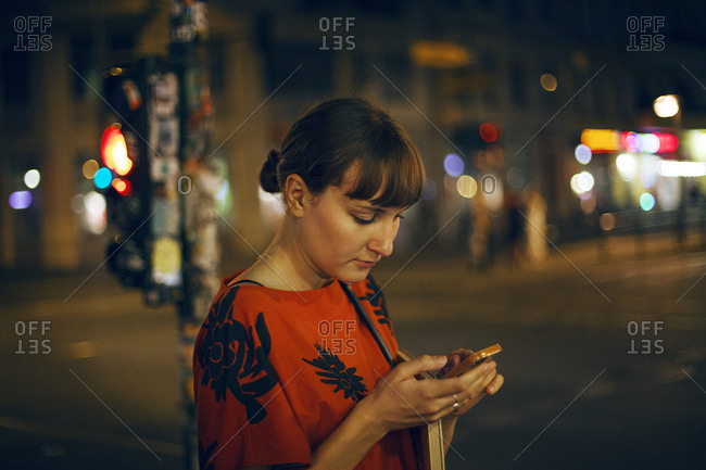 Germany, Berlin, Beautiful woman texting in city at night