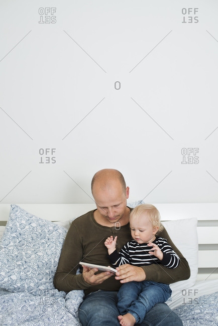 Sweden, Stay at home dad using tablet while holding son