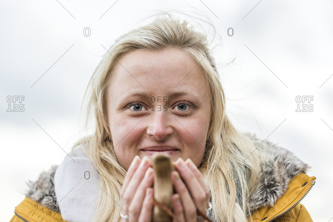 Sweden, Sodermanland, Portrait of young blonde woman holding coffee
