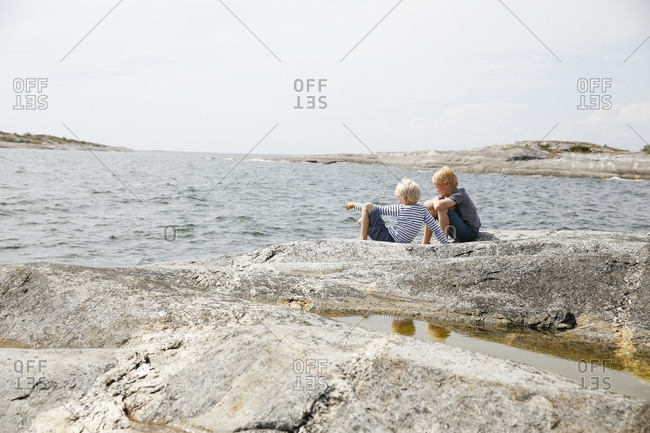 Sweden, Stockholm Archipelago, Sodermanland, Orno, Two boys sitting on rocky seashore