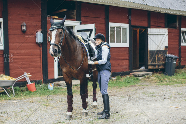 Sweden, Blekinge, Mid adult woman and horse in front of stable