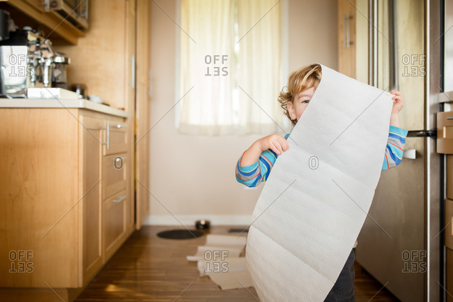 Toddler playing with paper towels in the kitchen