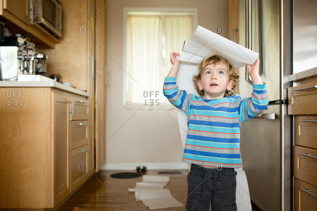 Toddler playing with paper towels in the kitchen