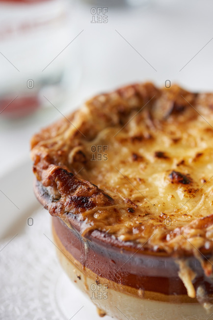 French Onion Soup with melted cheese on top, bubbling over the sides served at a French restaurant.