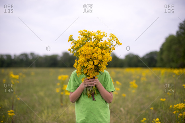Boy covering face with wildflowers