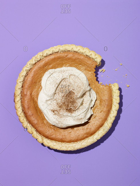 Whole pumpkin pie with whipped cream and bite missing