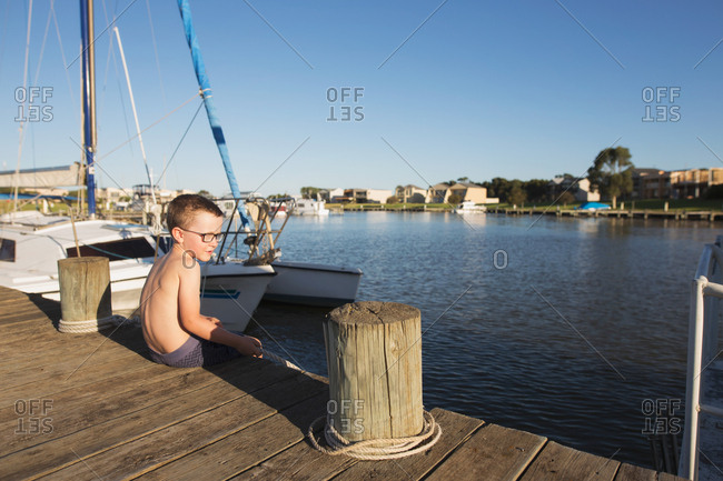 Boy sitting by boat on boardwalk