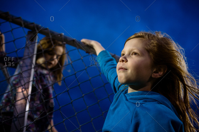 Determined young girls climbing a fence at night