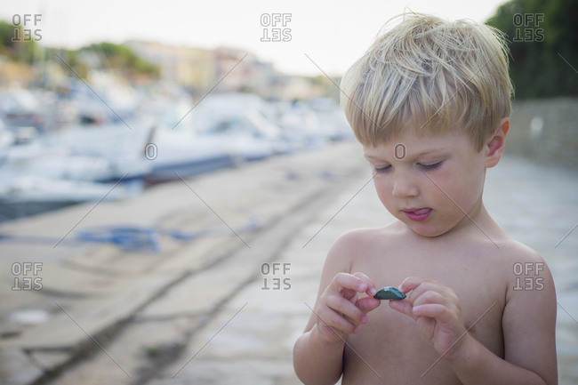 Curious Caucasian boy playing with rock