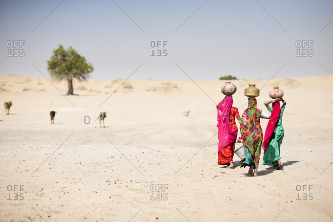 Women carrying water in traditional baskets in remote desert