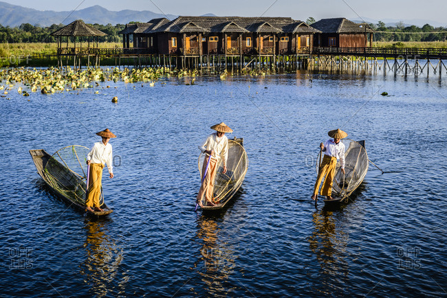 Asian fishermen fishing in canoes on river
