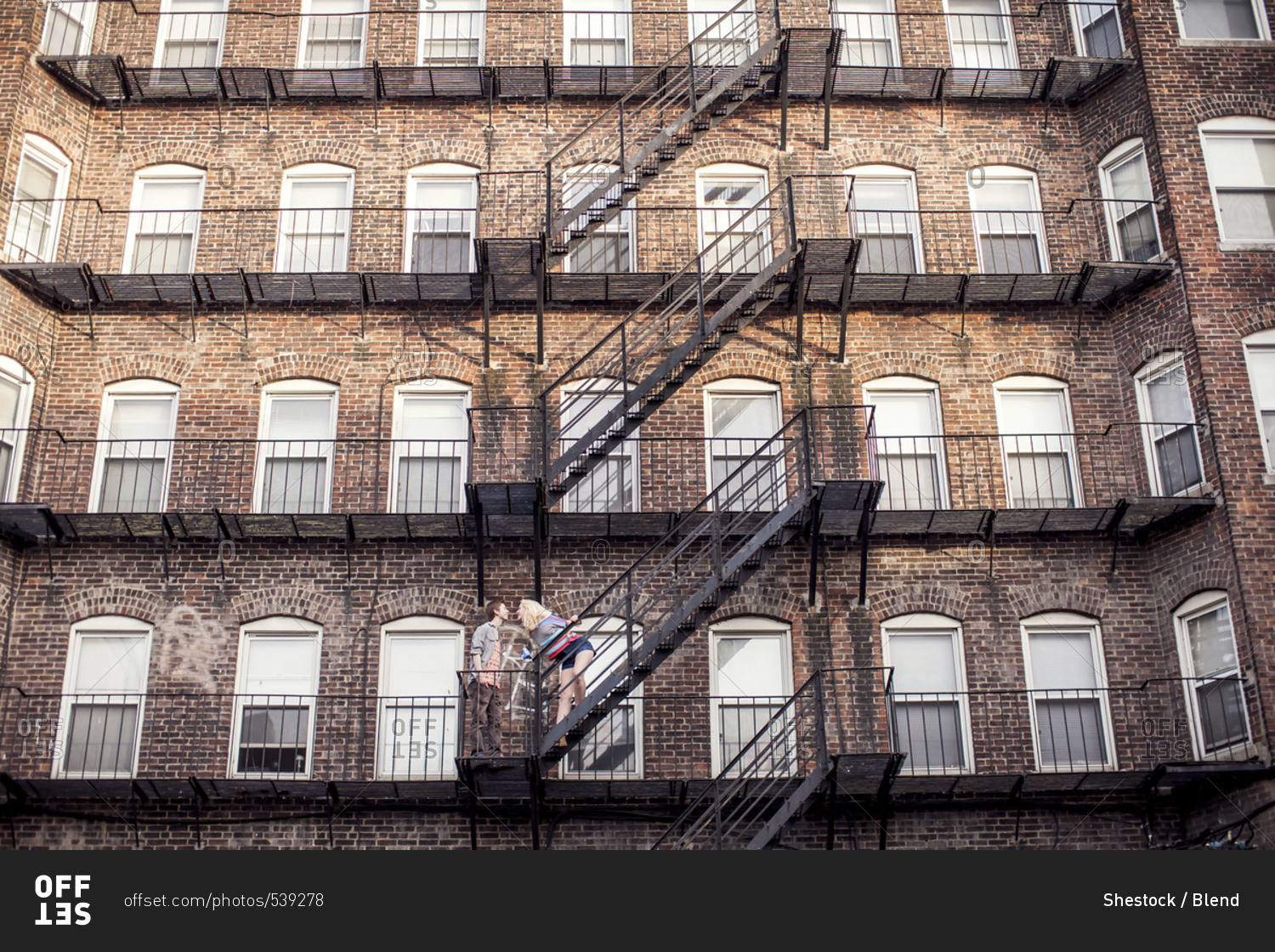 Caucasian couple standing on apartment fire escape