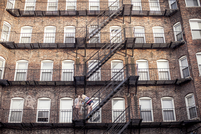 Caucasian couple standing on apartment fire escape