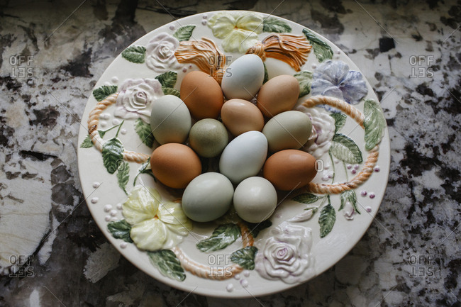 Fresh multi colored eggs in a ceramic floral bowl