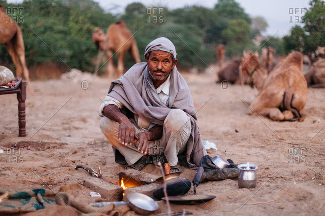 November 14, 2015 - Pushkar, India: A man sits by a fire in the early morning on the dunes of the Pushkar Camel Fair