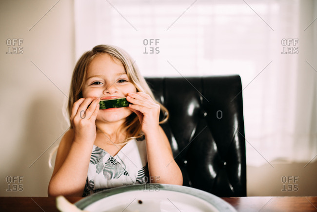 Girl eating a piece of watermelon down to the rind
