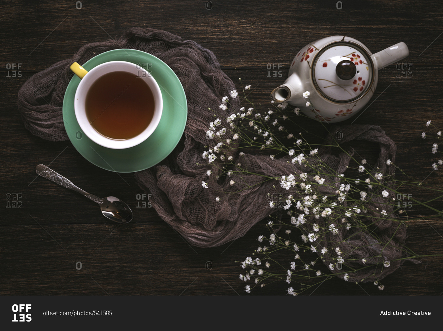Cup of tea with Floral background with red and white tulips and daisies, and green leaves on brown background, Flat lay, top view