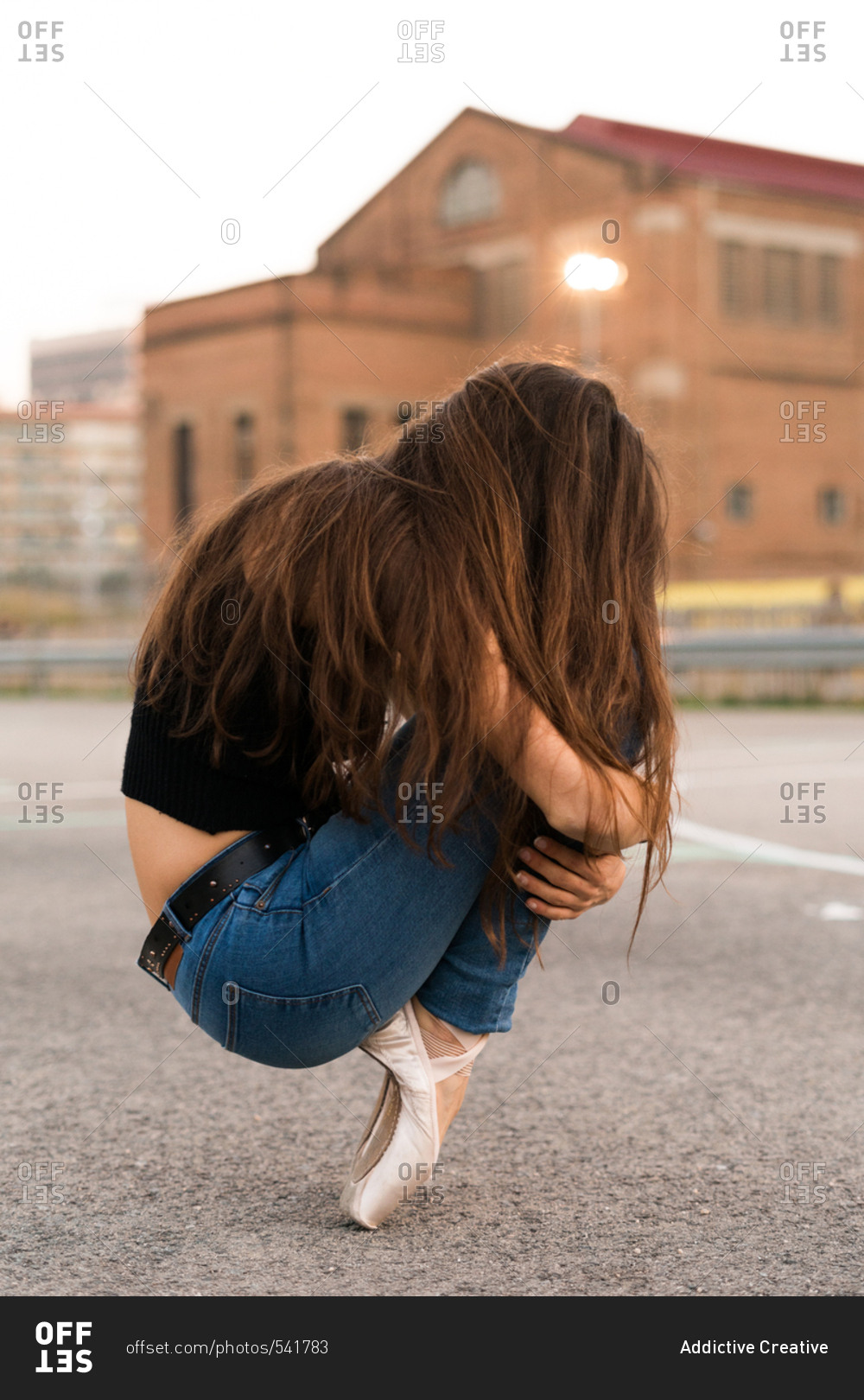 Side view of an unrecognizable woman sitting on a tiptoe on a playground,