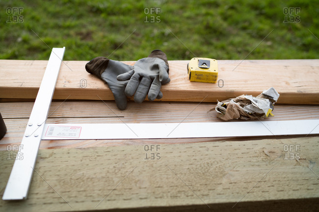 Gloves, T-square, and tape measure resting on lumber