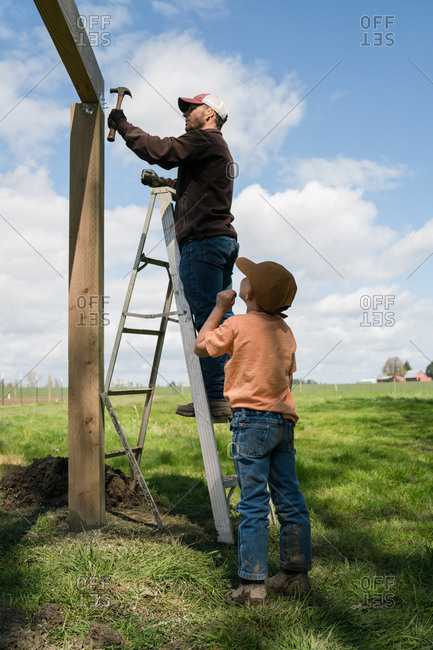 Man watching his father nailing bracket on wooden frame