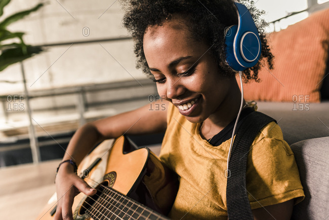 Woman With Guitar And Headphones Lying On Floor Stock Photo