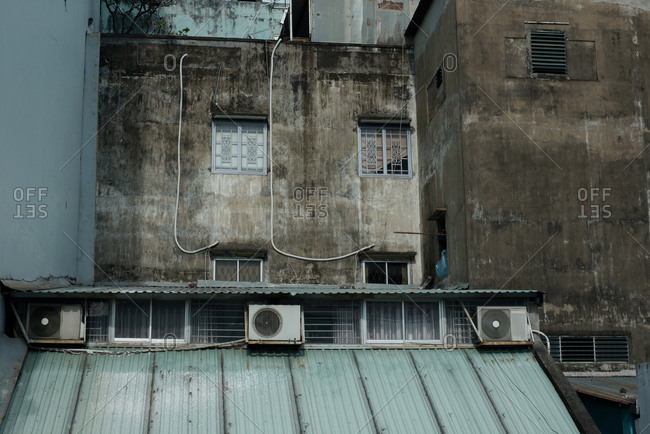 Old residential building with gray shabby walls and air conditioner units hanging outside