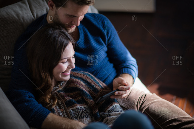 Couple looking at smartphone on sofa