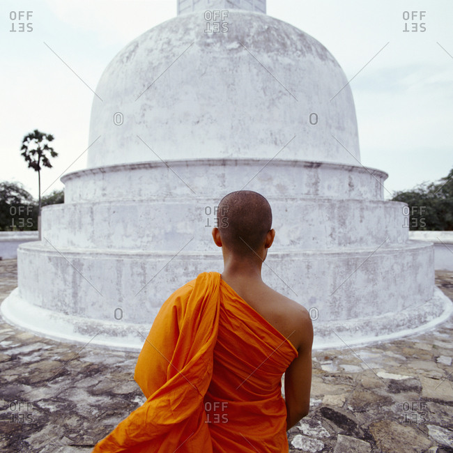 Buddhist monk standing in front of stupa