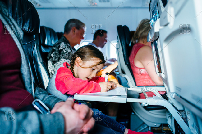 Girl coloring with markers on airplane