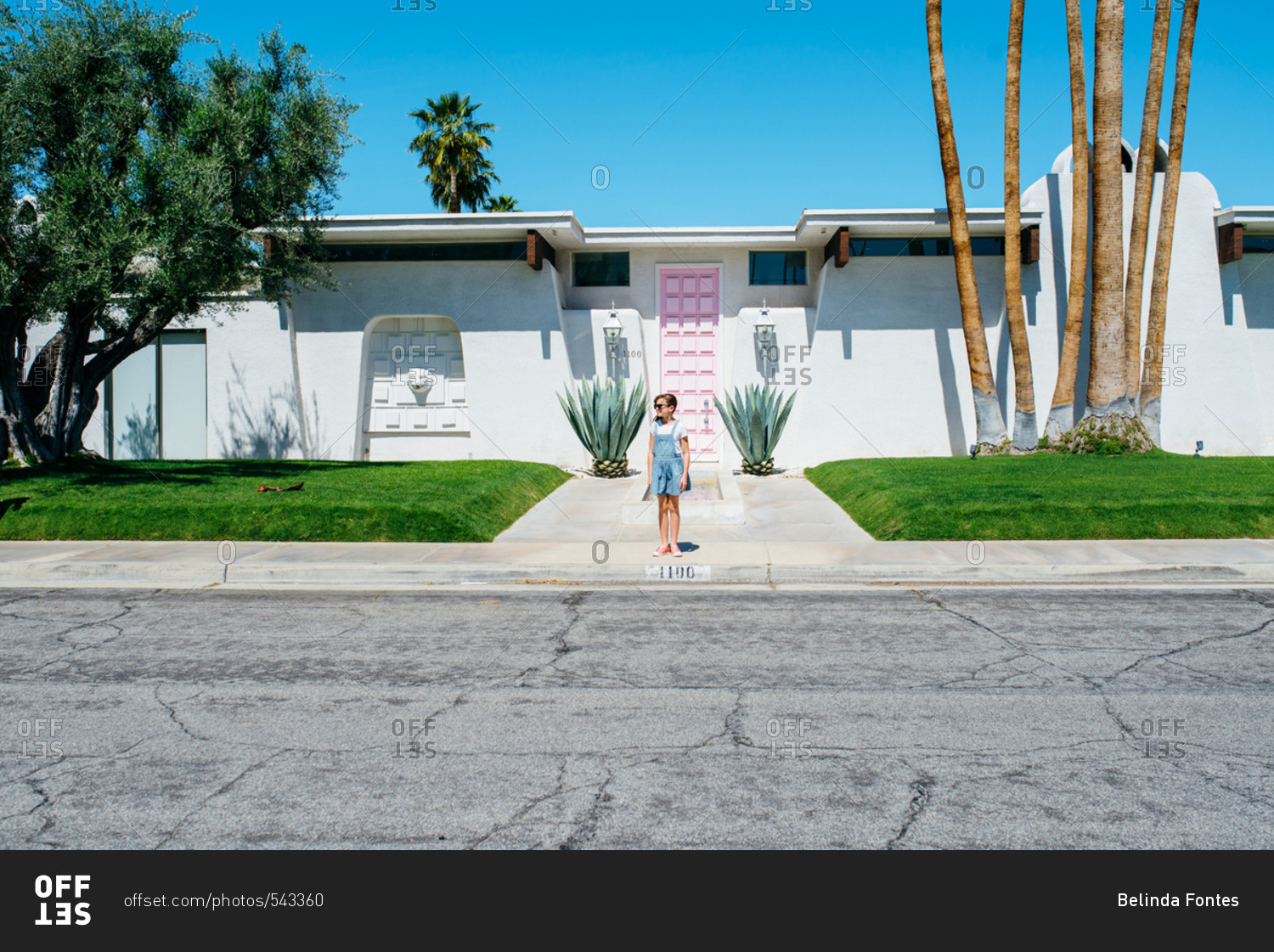 Girl standing on sidewalk in front of mid-century modern house
