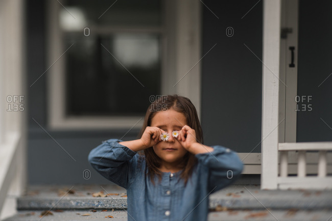 Girl holding daisies in front of her eyes