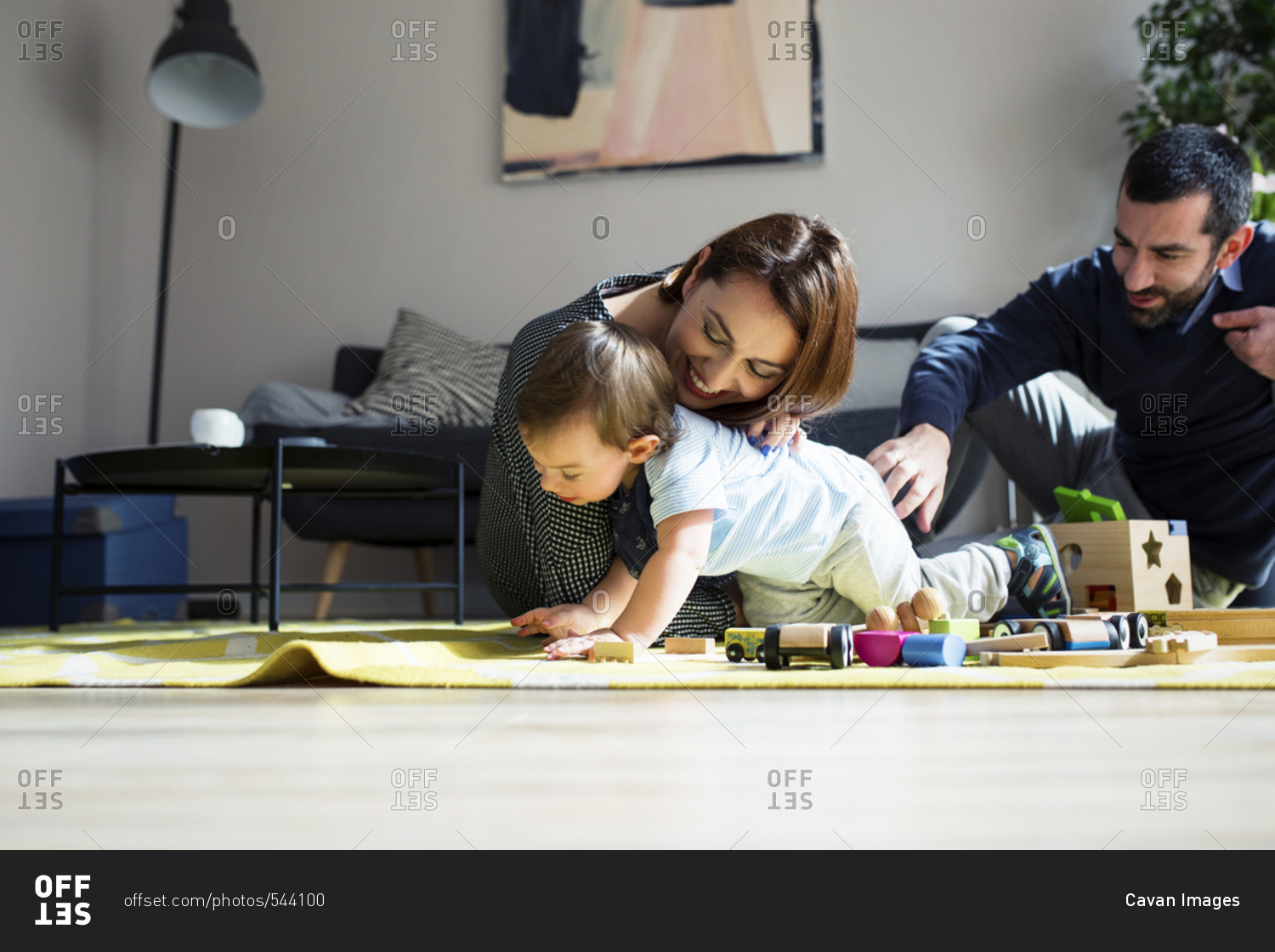 Parents and son playing with toy train at home