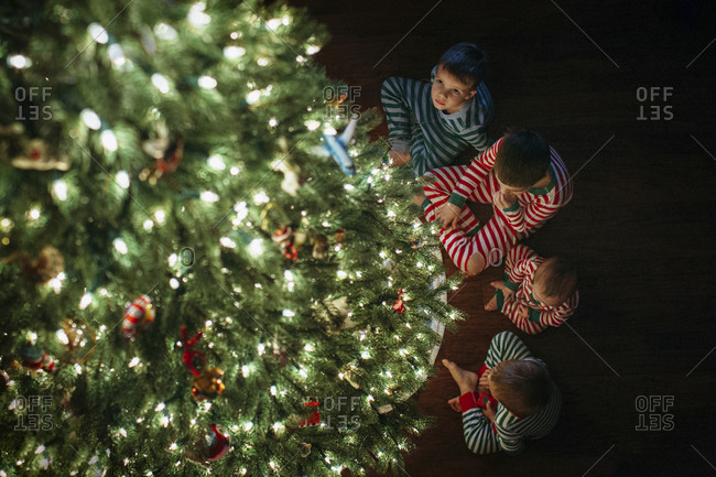 High angle view of siblings sitting by Christmas tree at home