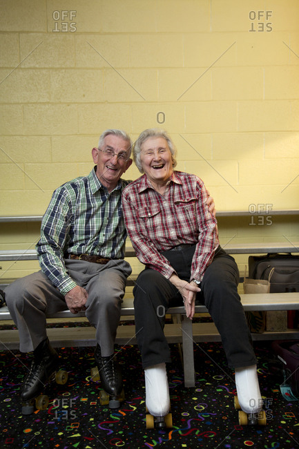 Portrait of happy senior couple sitting on bench at roller rink